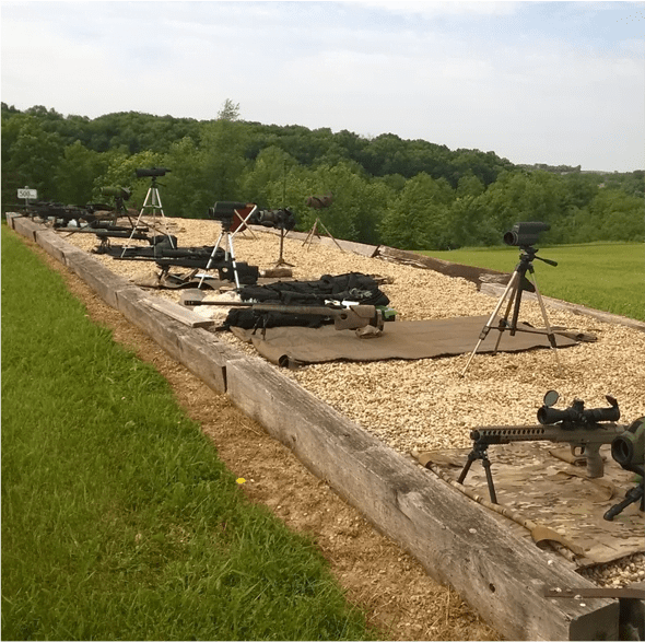A long row of guns on top of a dirt field.