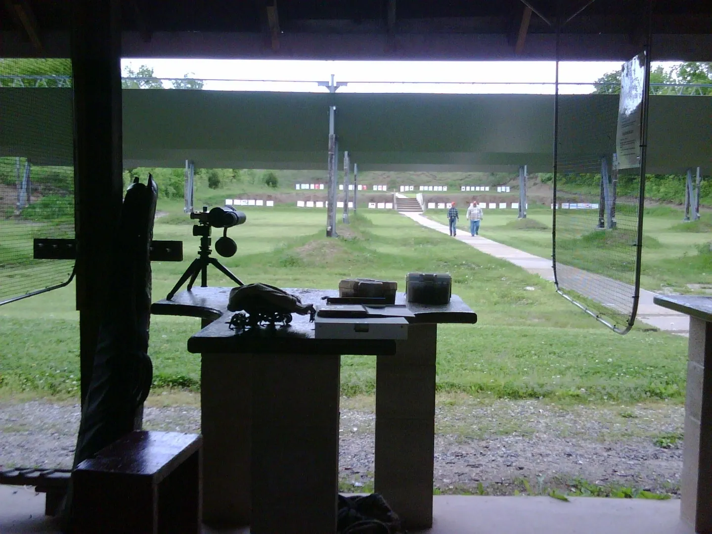 A table with a camera and tripod in front of a gun range.